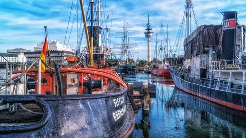 Fishing boats moored at harbor against sky