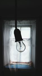 Close-up of light bulb against covered window at home