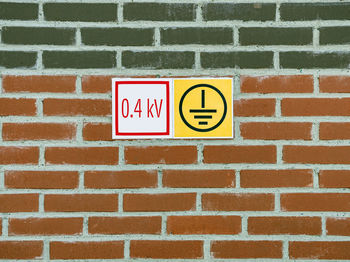 Electrical safety signs on the brick wall of the building. grounding and high voltage signs.