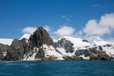 Scenic view of snowcapped mountains by sea against sky