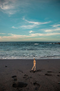 A wooden dummy walks along the beach with black sand