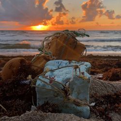 Close-up of abandoned beach against sky during sunset