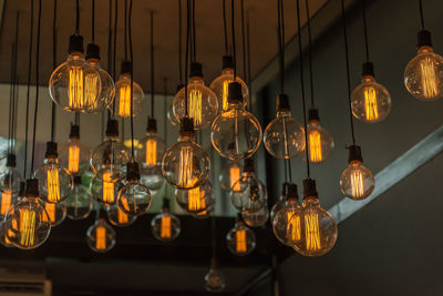 Low angle view of illuminated light bulbs hanging from ceiling