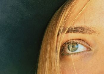 Cropped image of woman with green eyes against wall