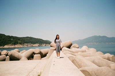 Woman standing on pier by sea against sky