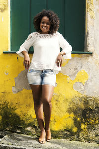 Model in a yellow dress smiling, looking and posing at the camera. 