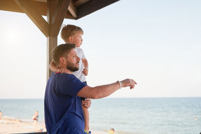 Boy enjoying on beach against sky
