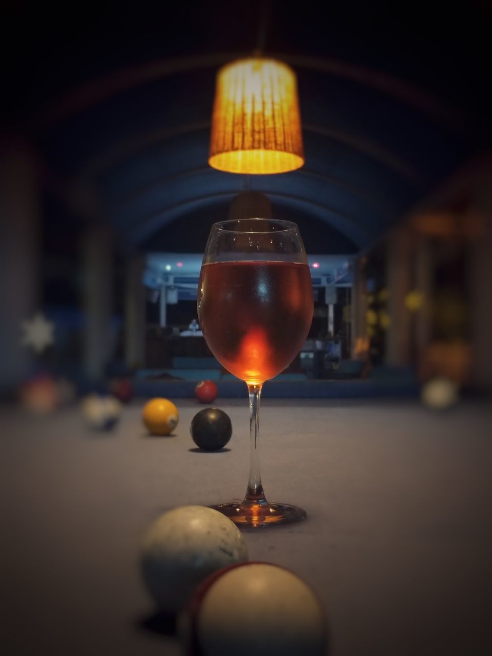 CLOSE-UP OF WINE GLASS IN ILLUMINATED ROOM