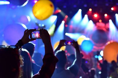 Close-up of hands photographing at music concert