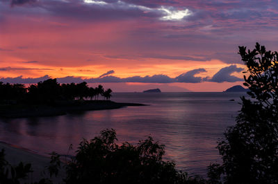 Scenic view of river amidst silhouette trees against cloudy sky during sunset