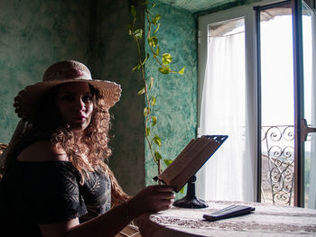 Woman reading book on table at home