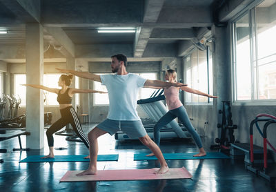 Man and women exercising while standing in gym