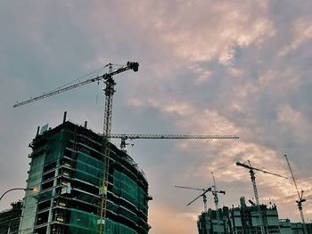 Low angle view of crane against cloudy sky