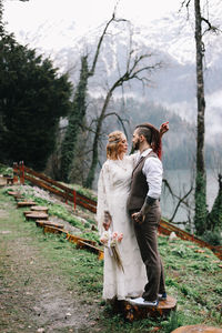 A loving married couple the bride and groom in suits celebrate wedding near the mountains and water