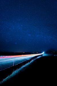 Light trails on road against star field at night
