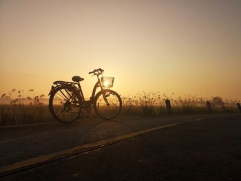 Bicycle on street against clear sky during sunset