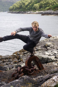 Portrait of young man balancing on metal at beach