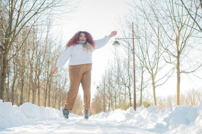 Full length of young woman standing on snow covered field