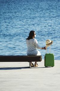 Rear view of woman sitting on seat at beach