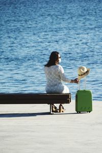 Rear view of woman with face mask sitting on seat at beach