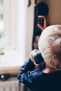 Close-up of cute boy talking on telephone at home