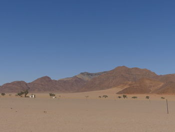 Scenic view of desert against clear blue sky