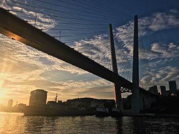 Silhouette bridge over river against sky during sunset