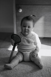 Cute baby girl sitting on carpet at home