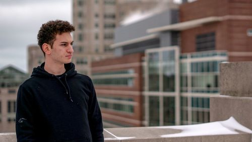 Young man looking away in city