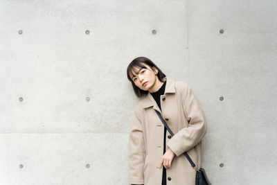 Young woman standing against wall