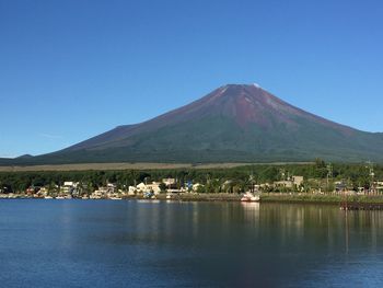 Scenic view of lake and mountains against clear blue sky