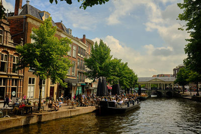 People in canal amidst buildings in city