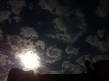 Low angle view of sun shining through clouds