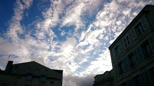 Low angle view of buildings against cloudy sky