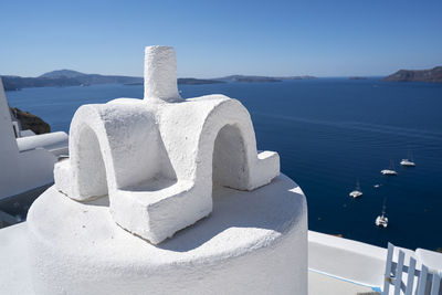 Built structure by sea against clear blue sky at santorini