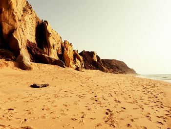 Rock formations on beach against clear sky