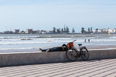 Man with bicycle lying on retaining wall against
