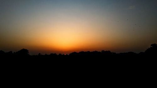 Scenic view of silhouette landscape against orange sky