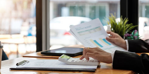 Midsection of woman reading book on table in restaurant