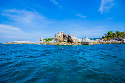 Scenic view of rocks in sea against blue sky