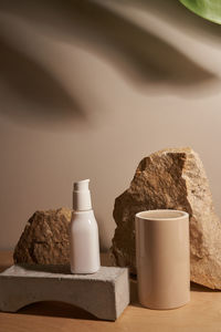 White ceramic opaque bottle on a beige background, natural podium, stones product display 