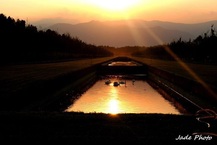 sunset, sun, mountain, tranquil scene, orange color, scenics, sunlight, sunbeam, tranquility, beauty in nature, water, reflection, sky, silhouette, lens flare, river, nature, tree, transportation, idyllic