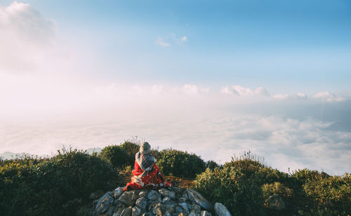 Man sitting by plants against sky