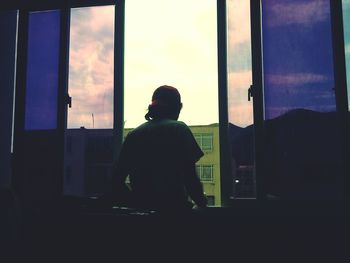 Rear view of a man looking through window