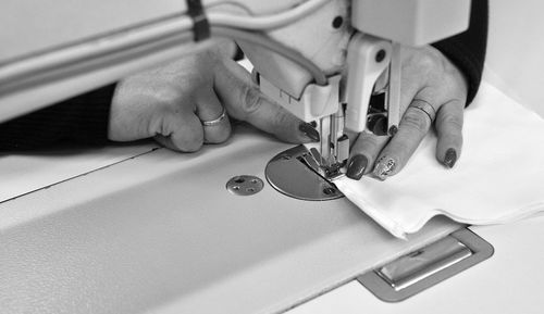 Cropped hands of woman sewing textile in factory