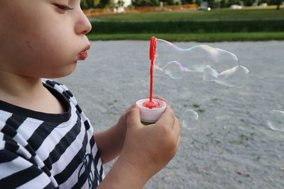 Close-up of cute girl blowing bubbles in park