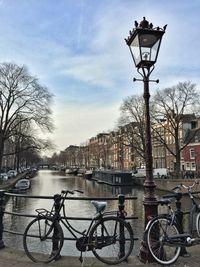 Bicycle by water in city against sky