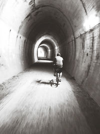 Rear view of man riding motorcycle in tunnel