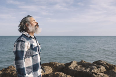 Side view portrait of a bearded man breathing fresh air on the beach