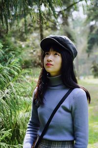Beautiful young woman wearing hat standing on land
